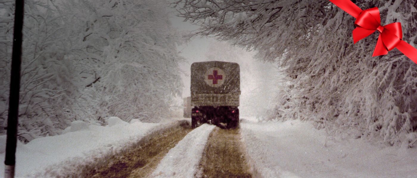 Un véhicule de la Croix-Rouge circulant sur une route enneigée.
