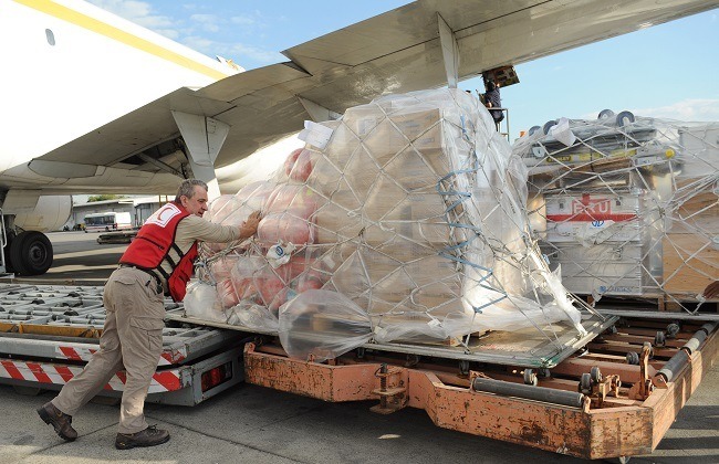 Un travailleur du Mouvement de la Croix-Rouge et du Croissant-Rouge décharge un avion transportant des articles de secours. 