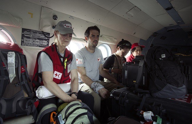 Des travailleurs humanitaires de la Croix-Rouge se déplacent à bord d’un hélicoptère. 