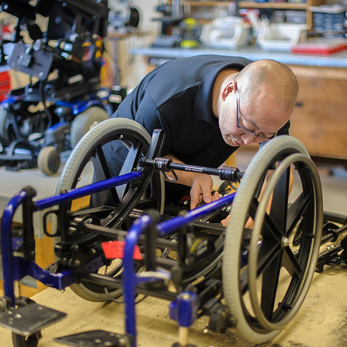 Un homme travaille à la remise à neuf d'un fauteuil roulant dans un atelier d'équipement de santé.
