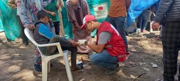 Red Crescent volunteer assisting with an injury