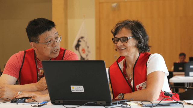 Deux bénévoles de la Croix-Rouge canadienne travaillant ensemble à l'aide d'un ordinateur portable