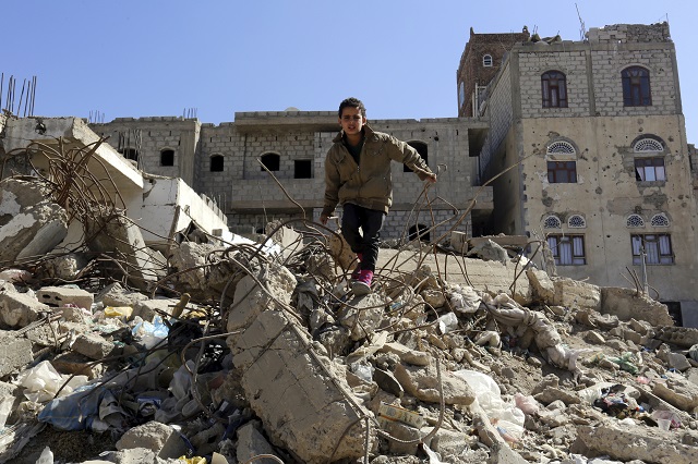 un jeune garçon grimpe sur le rouble dans une zone de guerre