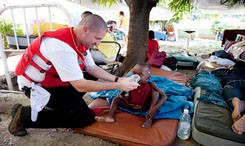 Un bénévole de la Croix-Rouge hydrate un enfant.