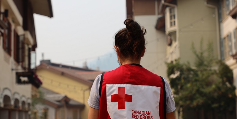 Femme dans une veste de la Croix-Rouge canadienne, le dos tourné à la caméra montrant le logo