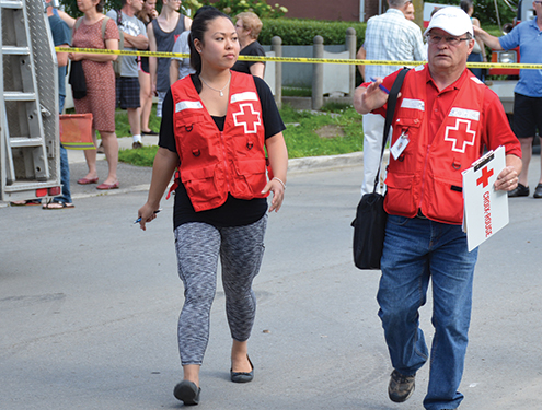 Deux bénévoles de la Croix-Rouge marchent et parlent ensemble à l'extérieur.