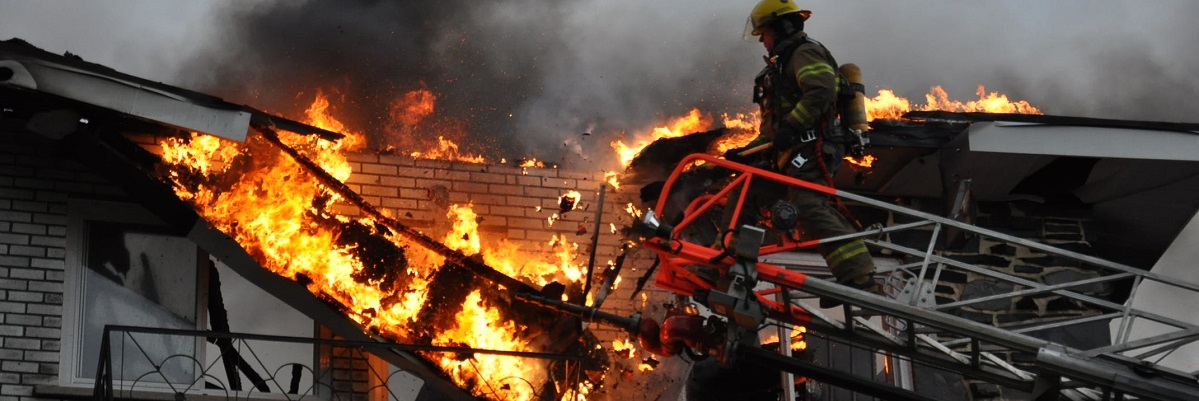 A fire engine parked in front of a row of houses Un pompier sur une échelle éteint un feu de bâtiment