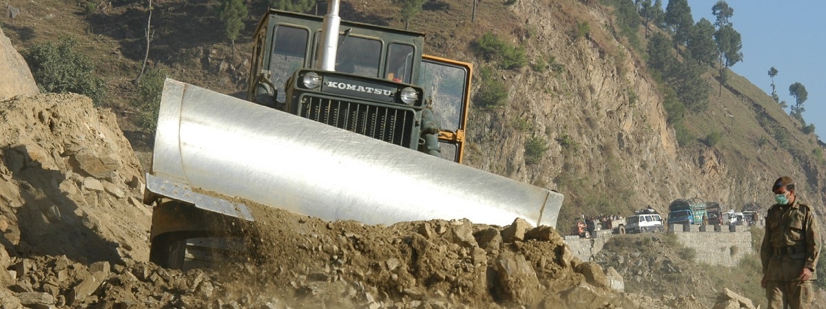 Un bulldozer efface les gravats d'une route à flanc de montagne