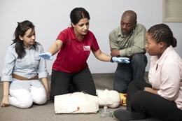 Femme enseignant trois personnes au-dessus d’un mannequin de CPR