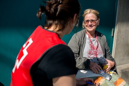 Une femme s’assoit et discute avec un bénévole de la Croix-Rouge