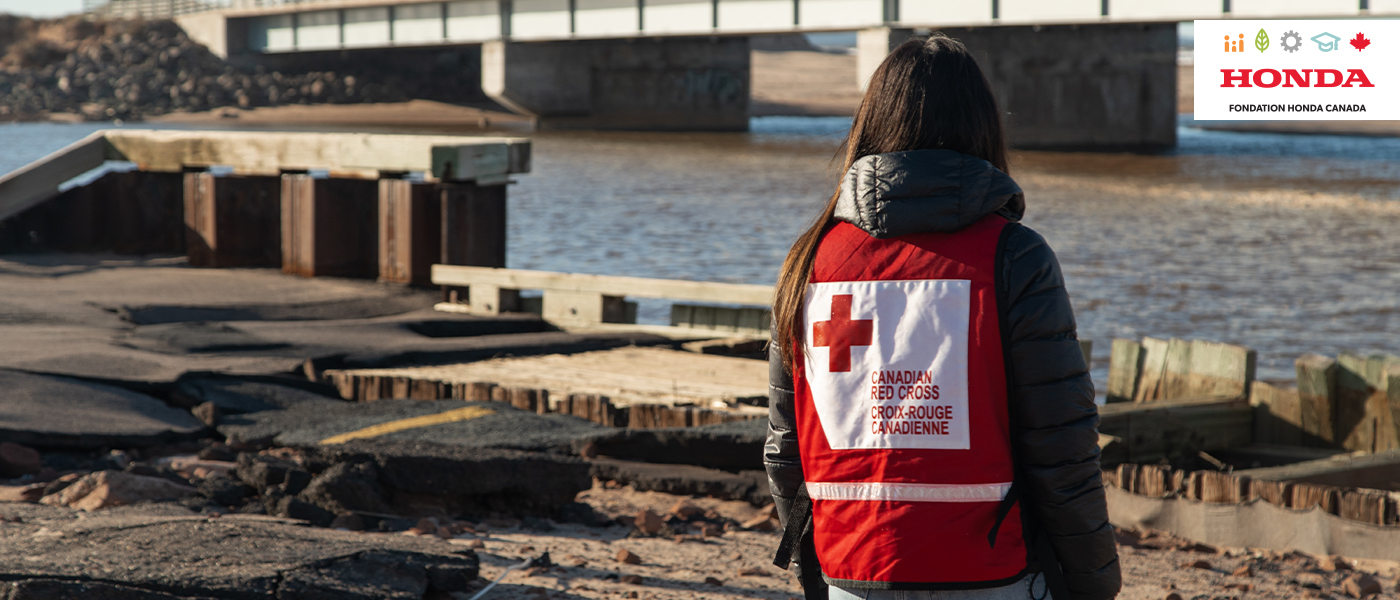 Une employée de la Croix-Rouge observe une route endommagée par la crue des eaux.