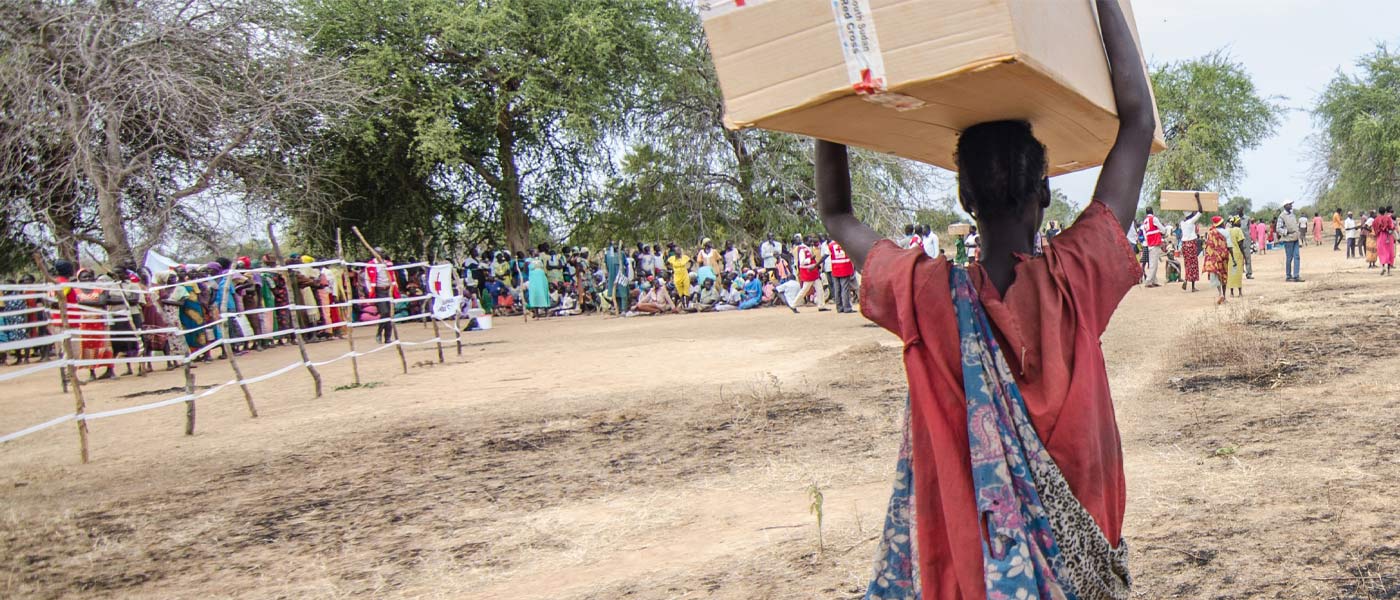 Un volontaire de la Croix-Rouge soudanaise prend des notes sur un bloc-notes, tandis qu'une mère tient son bébé.