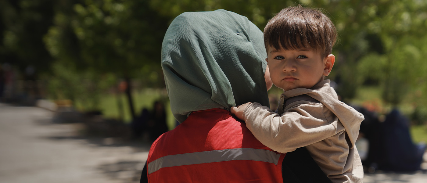 Un enfant afghan, dans les bras d’un membre du personnel de la Croix-Rouge/Croissant-Rouge.