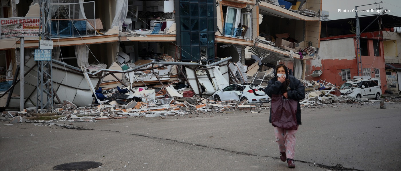 En Türkiye, une femme marche devant un immeuble détruit par les séismes qui ont secoué son pays.