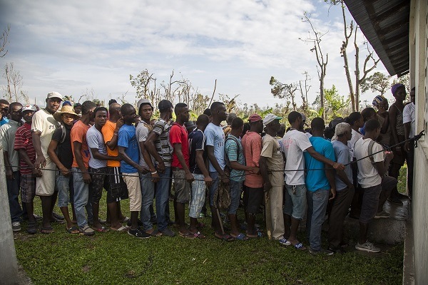 Des sinistrés font la file pour obtenir des trousses d’abri d’urgence au point de distribution pour les villes d’Arniquet et d’Antoine, en Haïti. 