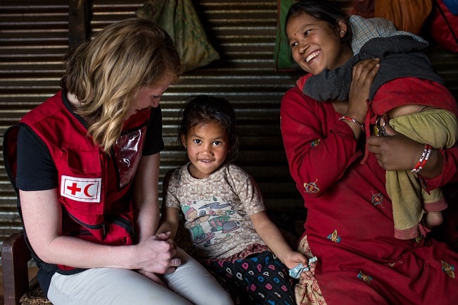 Une travailleuse humanitaire de la Croix-Rouge canadienne œuvrant au Népal discute avec une petite fille et sa mère.