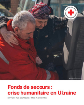 Un employé de la Croix-Rouge aide une femme à monter dans une voiture en Ukraine.