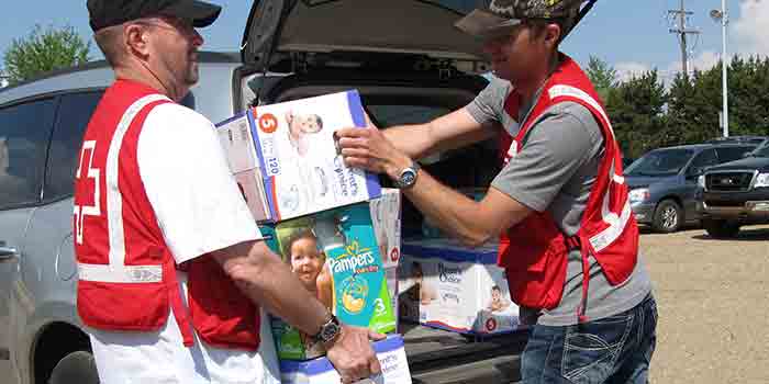 Deux bénévoles masculins de la Croix-Rouge déchargeant des couches