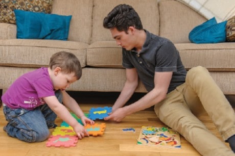 Une jeune fille et son père jouent au sol avec des jouets pour enfants