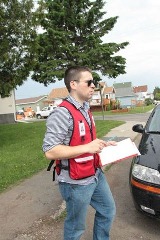 Oliver Whelan à l’extérieur tenant une planche à clip portant un gilet de la Croix-Rouge