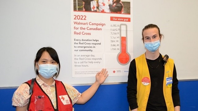 Un bénévole de la Croix-Rouge et un employé de Walmart devant une pancarte de campagne