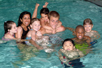 Deux adultes et sept enfants jouant dans une piscine 