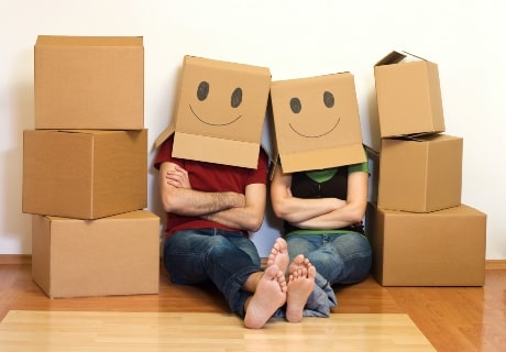 Un homme et une femme ont des boites de déménagement avec des sourires dessinés sur la tête. 