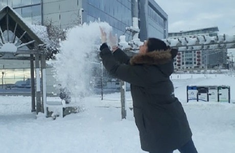 Une femme portant un manteau noir qui lance de la neige