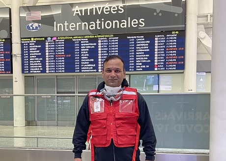 Un homme portant une veste de la Croix-Rouge canadienne dans la section des arrivées d'un aéroport.