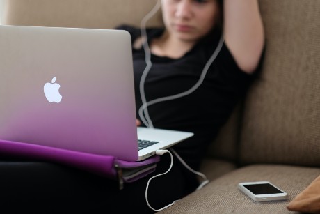 Une adolescente regarde son ordinateur avec des écouteurs dans les oreilles