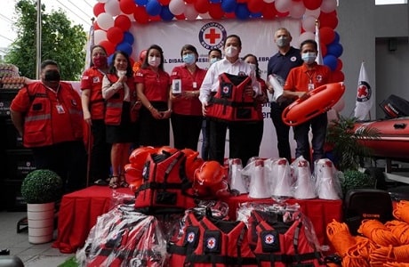 Des membres de la Croix-Rouge philippine posent pour des photos sur une scène, avec le matériel d'intervention d'urgence exposé.