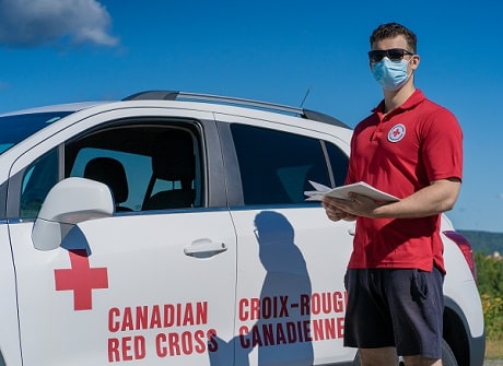 Joshua porte un chandail Croix-Rouge et pose pour la caméra avec un masque