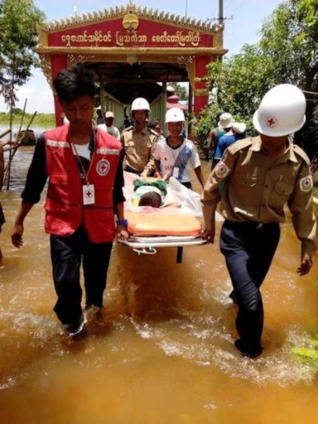 Des bénévoles Croix-Rouge accompagnant les sinistrés à travers un village inondé