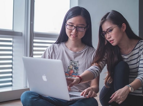 Deux jeunes femmes regardent l'écran d'un ordinateur portable.