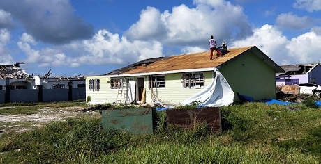 Deux hommes sur le toit d'une maison font une pause durant les travaux de réparation de leur maison.