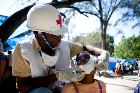 A Red Cross worker bandages a child's face in Haiti