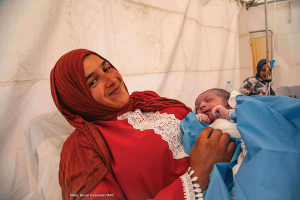 Une femme tient son nouveau-né dans une tente du Croissant-Rouge marocain.