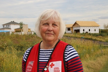 Debbie James, une bénévole de la Croix-Rouge canadienne, portant un dossard rouge, avec un champs derrière elle