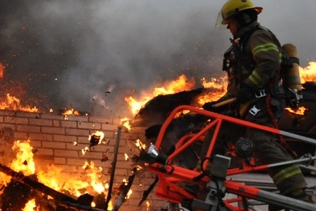 Un pompier sur le toit d'une résidence en feu