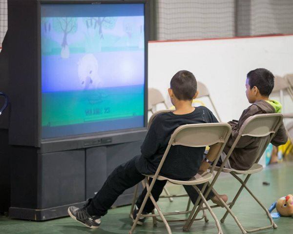 Deux enfants regardent la télévision dans un centre d'hébergement