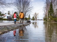 Deux personnes surveillent une route inondée