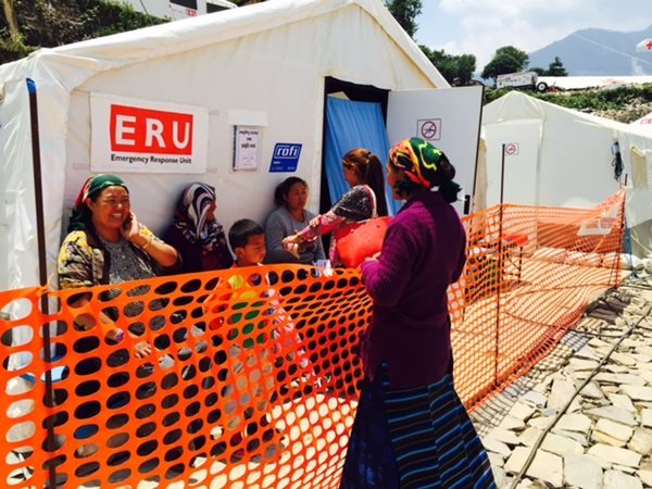 Cinq femmes et un enfant attendent leur tour à l'extérieur de la tente