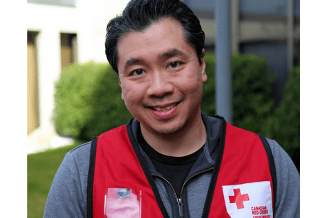 Un homme souriant portant une veste rouge de la Croix-Rouge