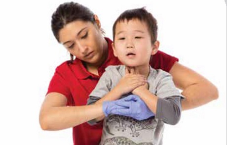 Une femme portant un chandail rouge fait une manoeuvre pour aider un enfant qui s'étouffe