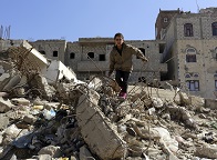 Young boy climbing over ruble in a war zone
