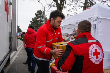 Deux hommes en uniforme du Mouvement de la Croix-Rouge travaillent