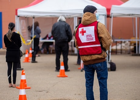 Un responsable de la Croix-Rouge de dos devant des tentes.