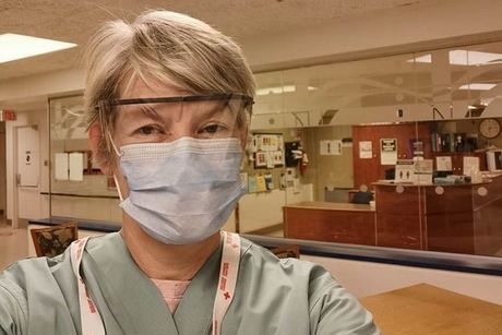 Une bénévole de la Croix-Rouge prend un selfie avec un masque et des lunettes de protection.
