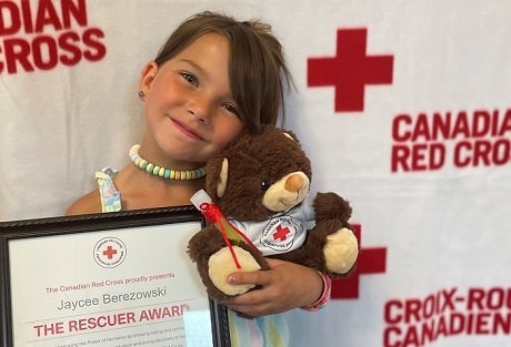 Jaycee Berezowski tient son prix et une peluche de la Croix-Rouge en souriant à la Caméra