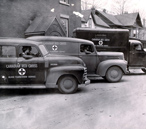 Trois voitures de la Croix-Rouge alignées dans la rue pendant la Seconde Guerre mondiale 